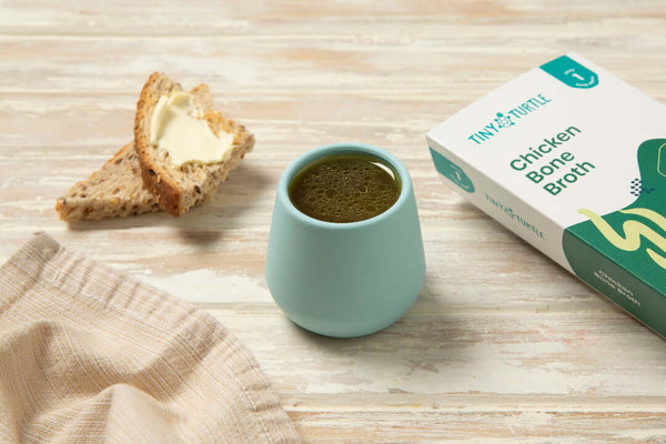 Tiny turtle chicken bone broth in a cup with some bread