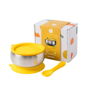 Yellow and silver bowl with lid and spoon next to its packaging on a white background