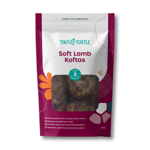 A package of Tiny Turtle Soft Lamb Koitas, stage 3, in a resealable stand-up pouch with a clear window showing the lamb balls inside. The packaging features a white and deep magenta design with orange and teal accents.