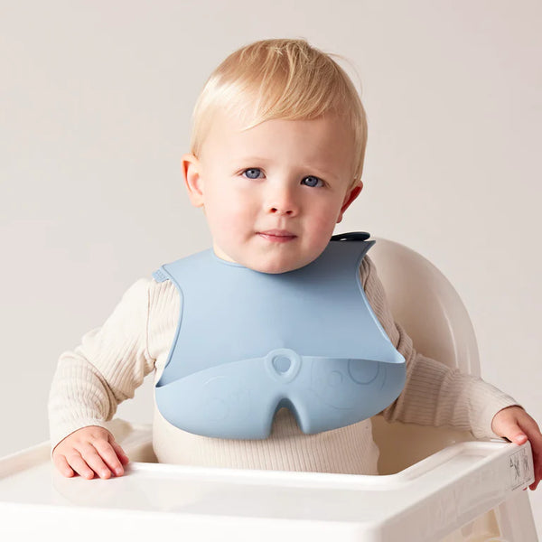 Bbox silicone bib on a baby in a high chair, designed to catch food, made of non-toxic silicone, easy to clean.