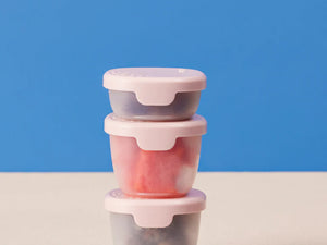 Three colorful b.box Snack Tubs stacked on a table, featuring secure hinged lids for yoghurts and dips.