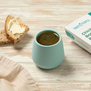 Tiny turtle chicken bone broth in a cup with some bread