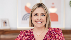 Woman in a floral blouse sitting on a couch with a blurred background
