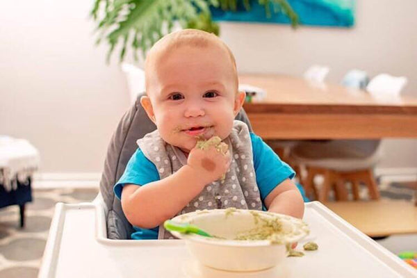Cute baby in a blue shirt enjoying tiny turtle purees