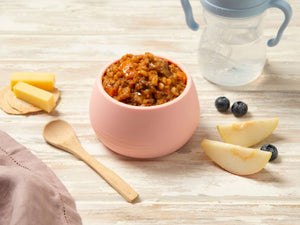 Bowl of slow cooked beef and barley puree with vegetables beside pear and blueberries, perfect for babies.