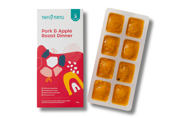 Pork and Apple Roast Dinner Stage 3 baby food by Tiny Turtle, featuring lumpy textured puree in tray next to packaging.