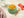 Bowl of stage 3 summer mango chicken with brown rice baby food with lumpy puree with watermelon pieces on a wooden surface.